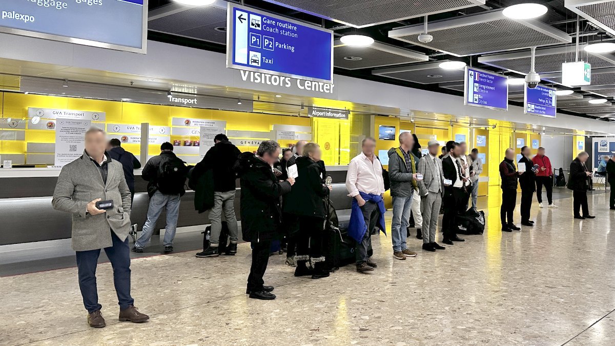 Driver meeting passengers with a name sign for a transfer from Geneva airport to Morges