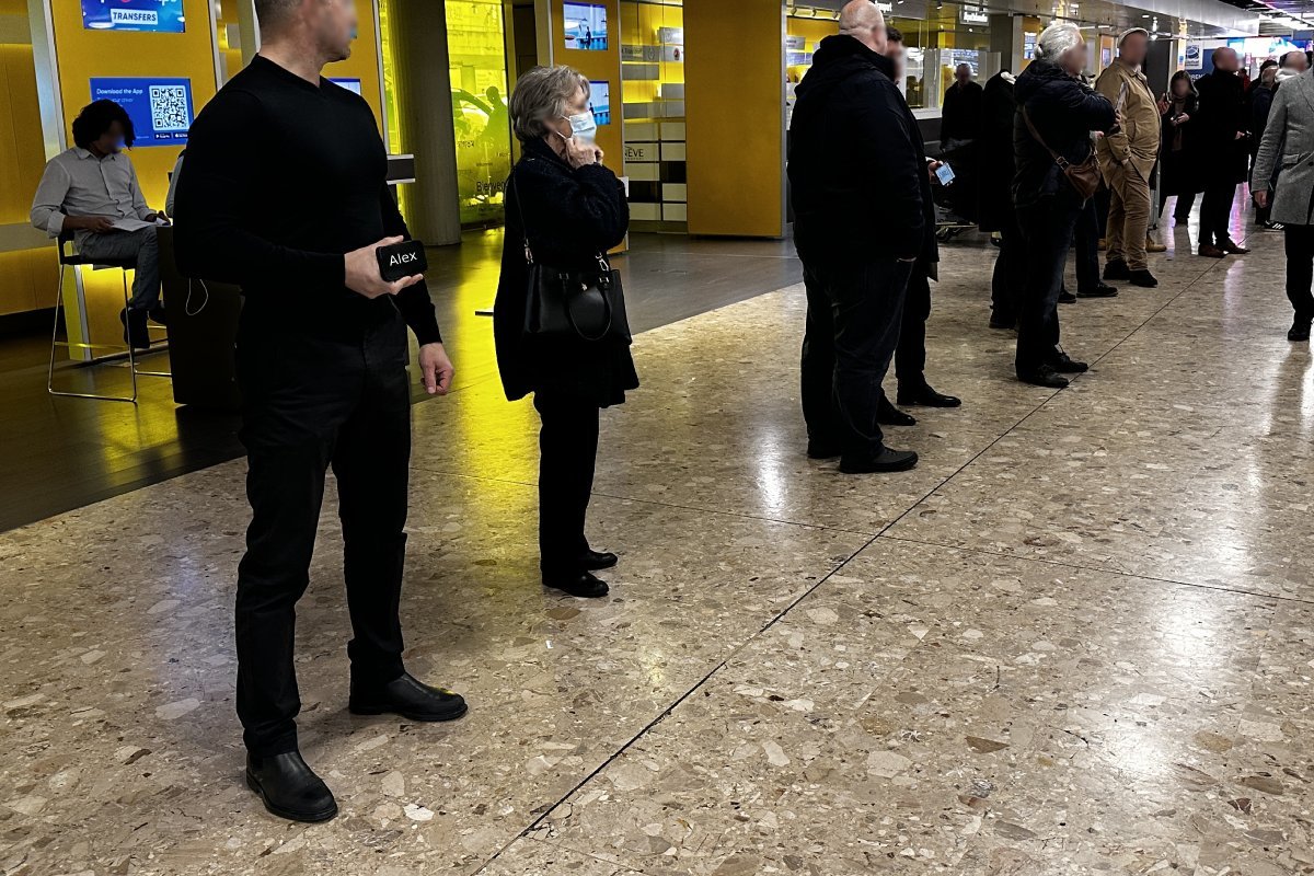 Driver meeting passengers with a name sign at Geneva Airport