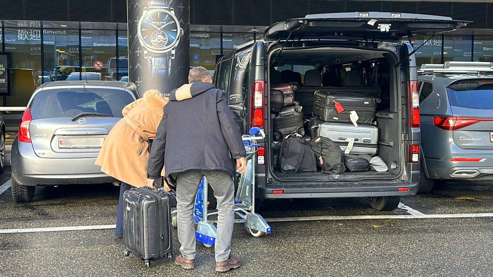 Loading suitcases into the trunk of a Renault Trafic at Geneva Airport for a transfer to Courchevel