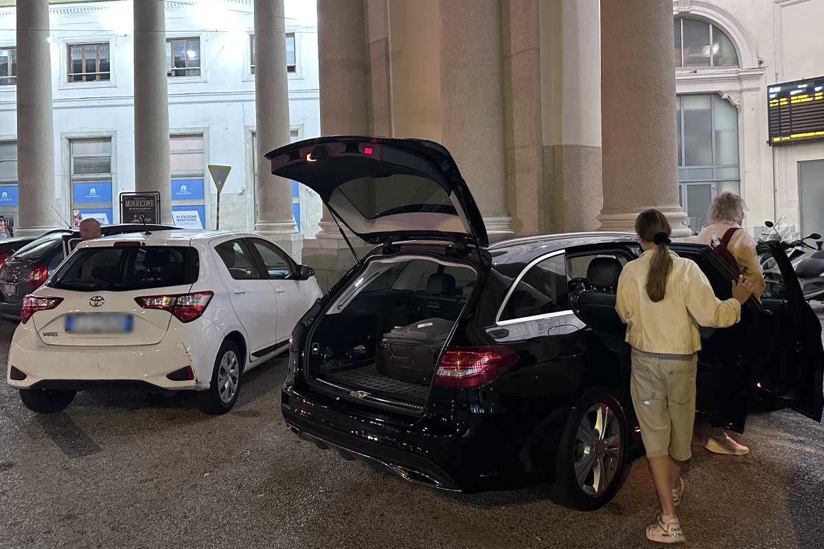 Driver meeting passengers at Genoa train station at night