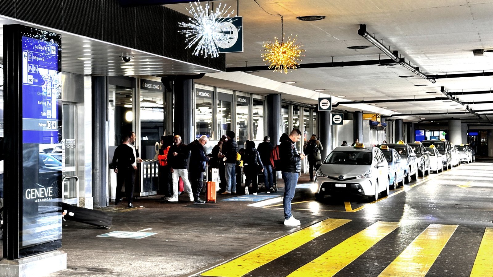 Taxi rank at Geneva Airport terminal with passenger waiting for a taxi to Courchevel