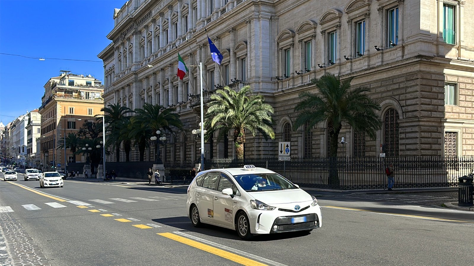 A taxi carries passengers along a street in Rome.